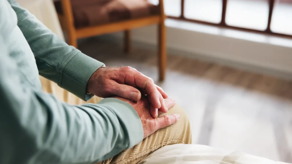 elderly man sitting and contemplating with hand on knee