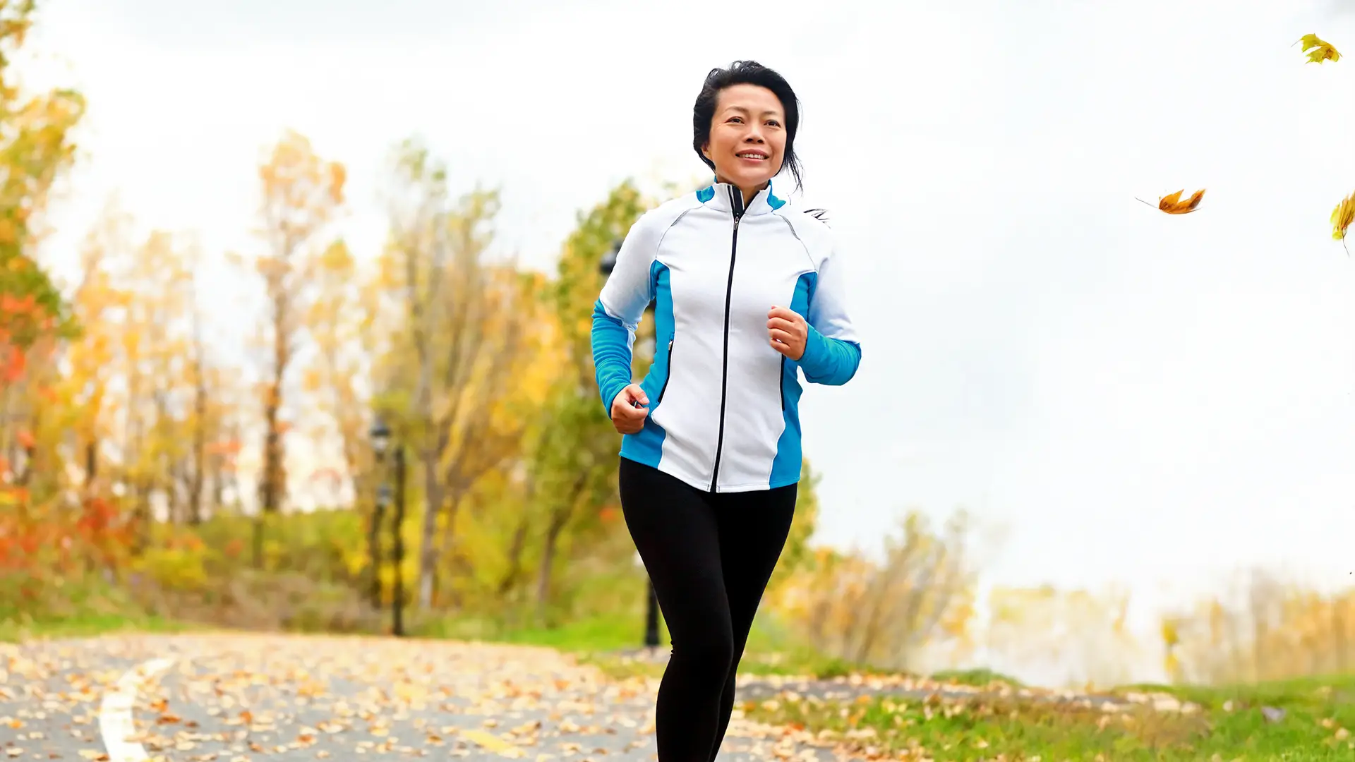 woman in her 50s running outside and smiling